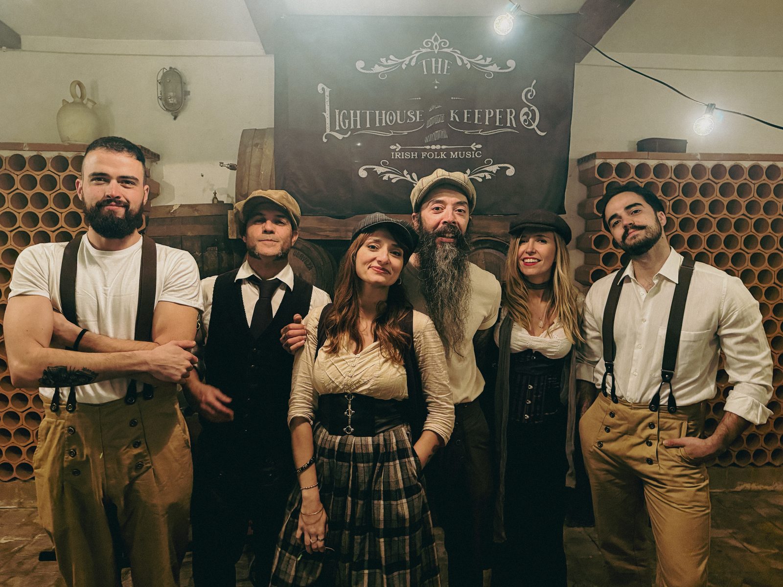 The Lighthouse Keepers posando frente a su lona con el logo de la banda